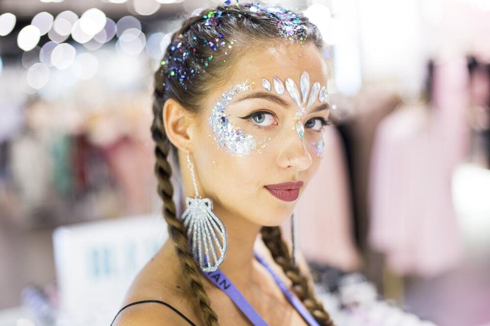 An image of a girl wearing festival makeup including large glitter gems